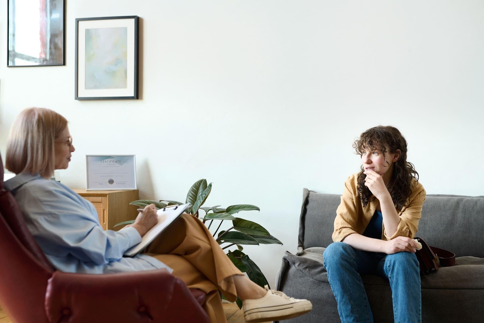 cbt in consultancy psychology A client sitting across from a professional CBT therapist in a bright, comfortable counseling room.
