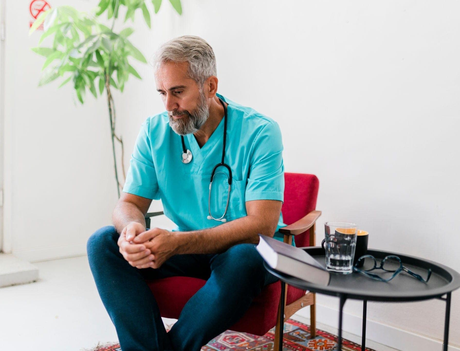 Why Healthcare Professionals Need Wellness Support doctors wellness program Indian doctor sitting quietly in a hospital break area with a calm, reflective expression. and counselling for doctors uk