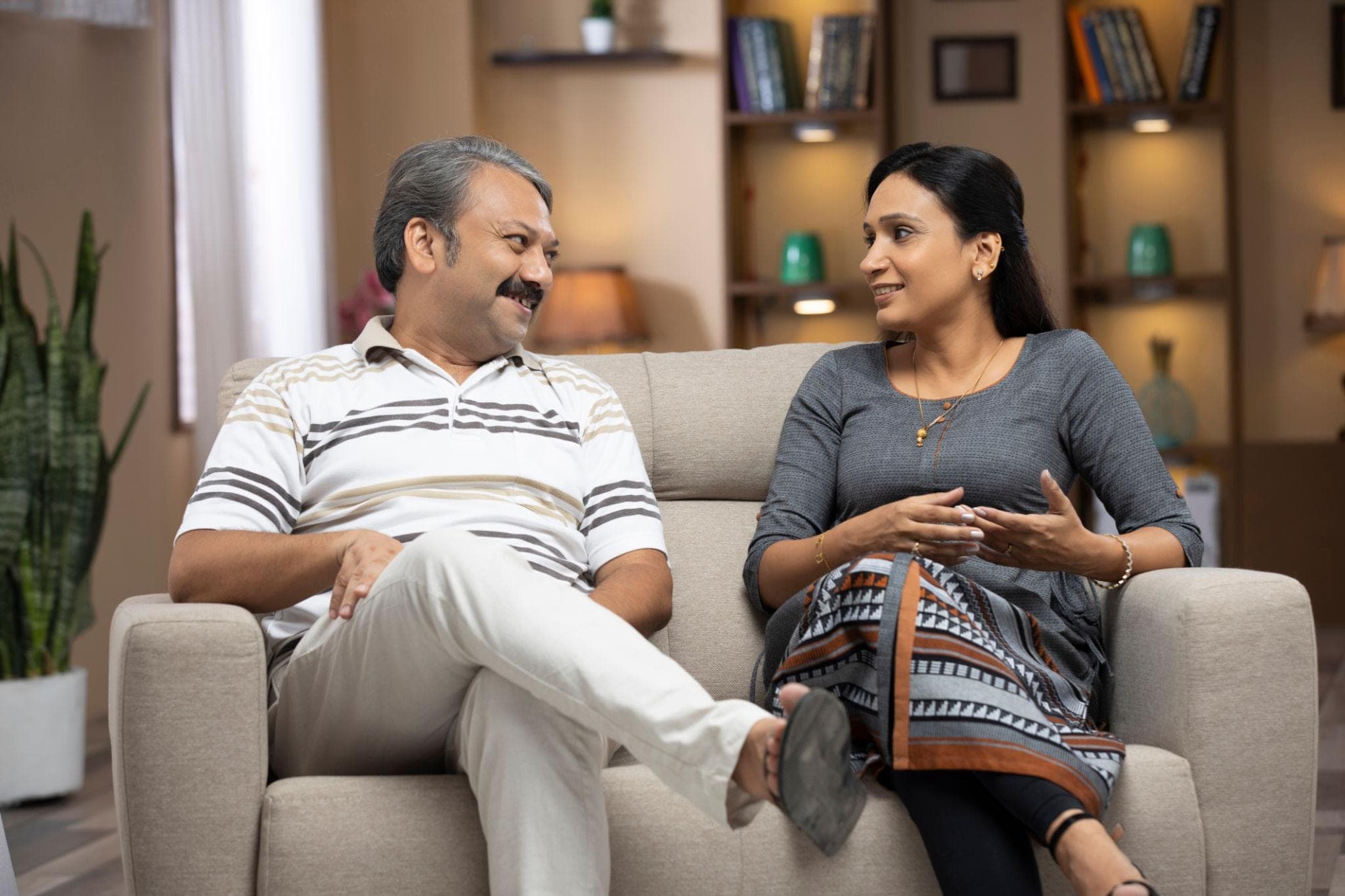 A married Indian couple sitting together in a comfortable, bright home environment, calmly talking and listening to each other., Couples Marriage Counseling A married Indian couple sitting together in a comfortable, bright home environment, calmly talking and listening to each other., Couples Marriage Counseling